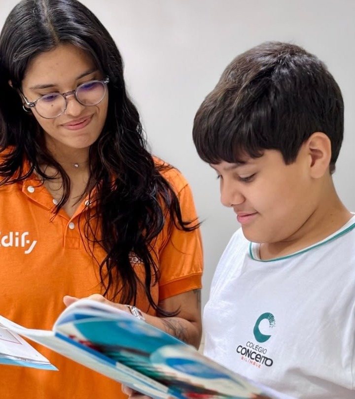 Professora e aluno do Colégio Conceito Bilíngue folheando o material didático juntos